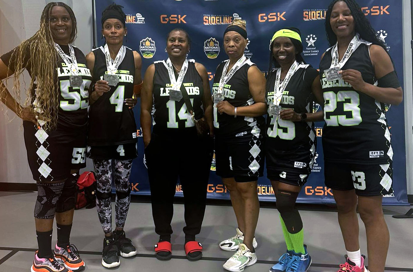 A group of women show off the medals they won in the basketball event.