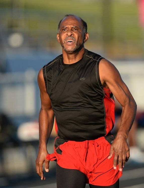 A man jumping in a track and field event as spectators look on.